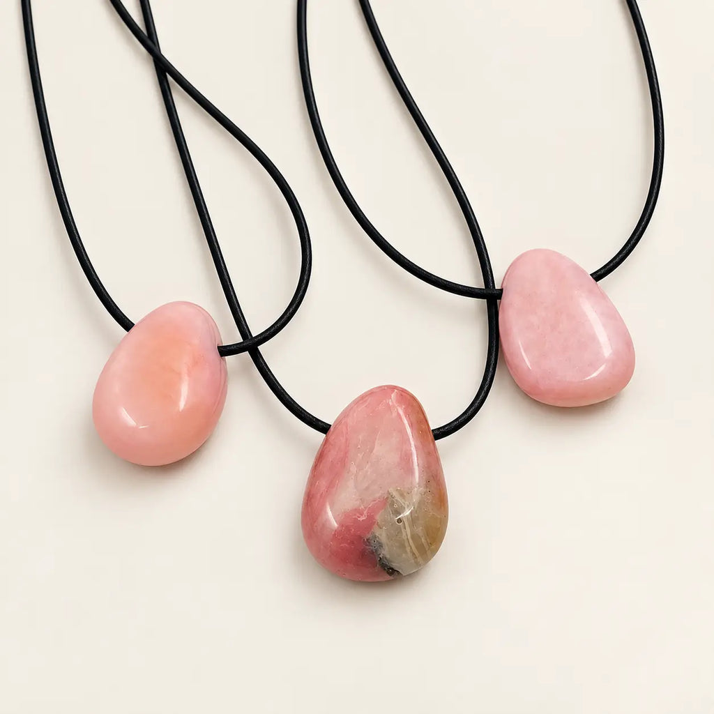 Trije Pink Opal obeski z vrvico na beli podlagi – pogled s sprednje strani, vidni različni odtenki rožnatega opala